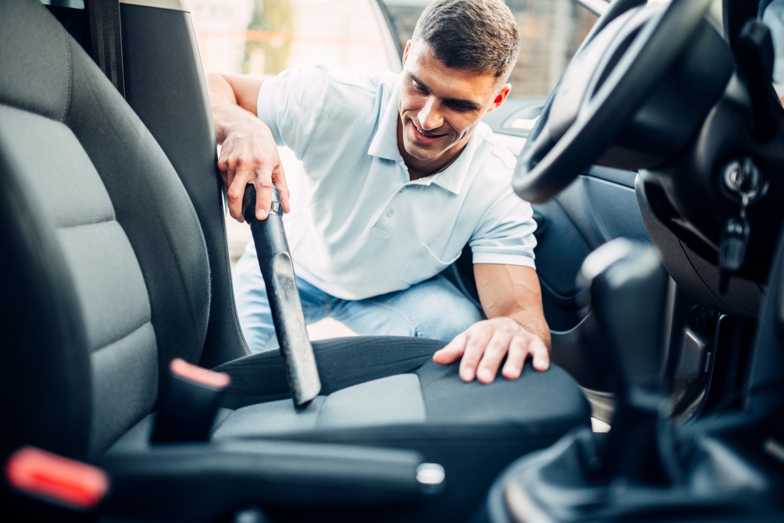 Man cleans car interior with vacuum cleaner