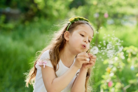 girl blowing dandelions flower selective focus. Allergy season.