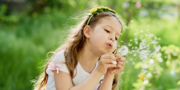 girl blowing dandelions flower selective focus. Allergy season.
