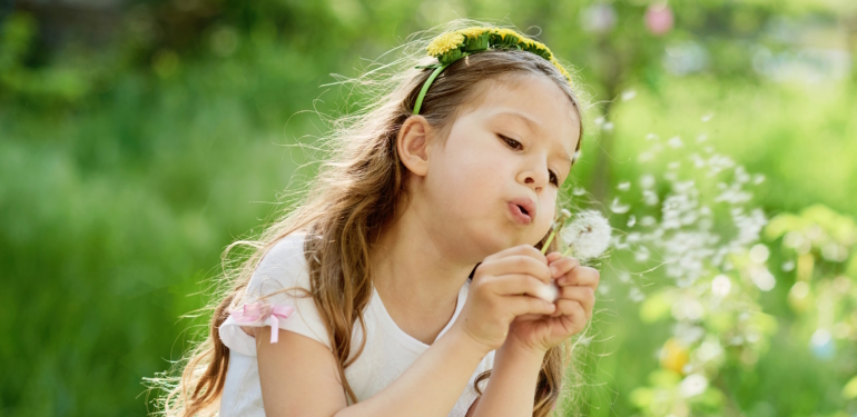 girl blowing dandelions flower selective focus. Allergy season.