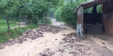 YAĞIŞ SONRASI MAHALLE YOLU ULAŞIMA KAPANDI YAĞIŞ İLE GELEN TAŞ VE ODUN PARÇALARI YOLU KAPLADI